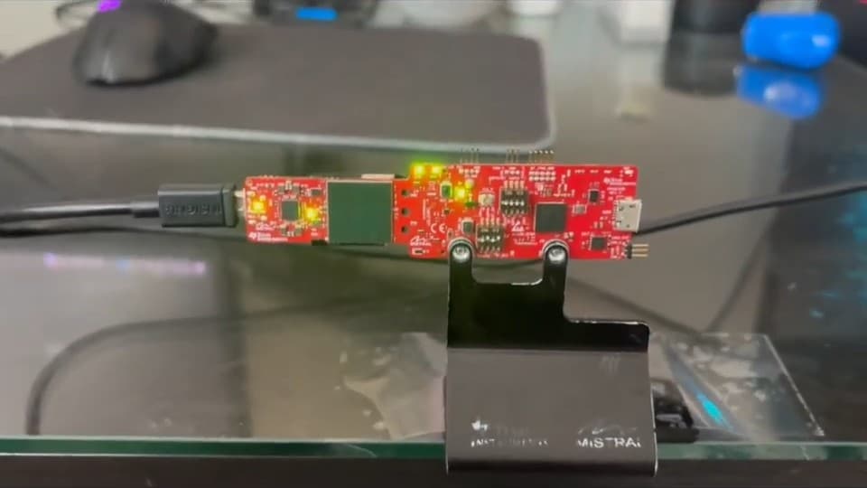 The TI IWR6843 radar evaluation board on a desk, its status LEDs lit, connected by USB.